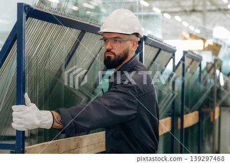 In white gloves, with windows. Warehouse worker in an industrial environment of a factory or storage area In white gloves, with windows. Warehouse worker in an industrial environment of a factory or storage area 139297468