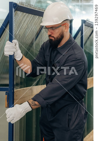 In white gloves, with windows. Warehouse worker in an industrial environment of a factory or storage area In white gloves, with windows. Warehouse worker in an industrial environment of a factory or storage area 139297469