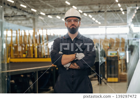 Arms crossed, standing. Warehouse worker in an industrial environment of a factory or storage area Arms crossed, standing. Warehouse worker in an industrial environment of a factory or storage area 139297472