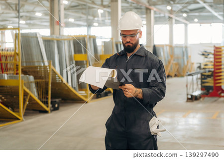 In professional protective hat. Warehouse worker in an industrial environment of a factory or storage area In professional protective hat. Warehouse worker in an industrial environment of a factory or storage area 139297490