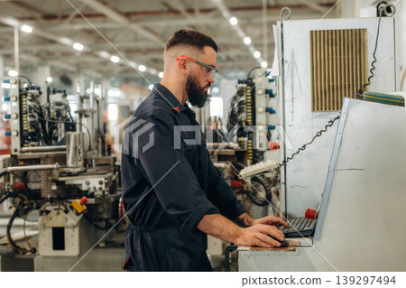 Focused, working by machine, the operator. Warehouse worker in an industrial environment of a factory or storage area Focused, working by machine, the operator. Warehouse worker in an industrial environment of a factory or storage area 139297494