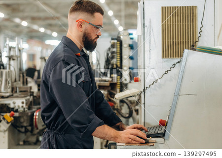 Focused, working by machine, the operator. Warehouse worker in an industrial environment of a factory or storage area Focused, working by machine, the operator. Warehouse worker in an industrial environment of a factory or storage area 139297495