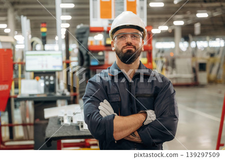 Arms crossed, standing. Warehouse worker in an industrial environment of a factory or storage area Arms crossed, standing. Warehouse worker in an industrial environment of a factory or storage area 139297509