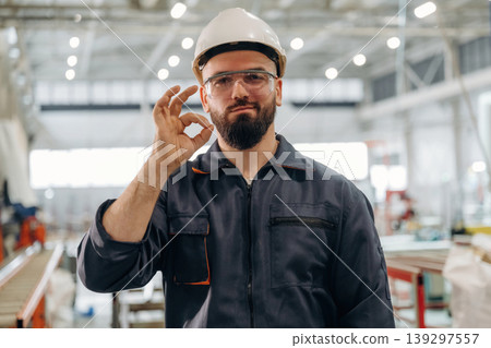 Okay hand gesture. Warehouse worker in an industrial environment of a factory or storage area Okay hand gesture. Warehouse worker in an industrial environment of a factory or storage area 139297557
