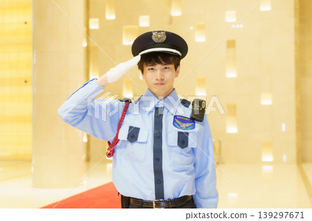 A young Japanese male security guard salutes. Photo courtesy of Denpa Gakuen Educational Foundation, Tokyo Electronics College. A young Japanese male security guard salutes. Photo courtesy of Denpa Gakuen Educational Foundation, Tokyo Electronics College. 139297671