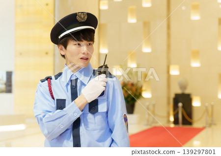 A young Japanese male security guard conversing on a walkie-talkie. Photo courtesy of Denpa Gakuen Educational Foundation, Tokyo Electronics College. A young Japanese male security guard conversing on a walkie-talkie. Photo courtesy of Denpa Gakuen Educational Foundation, Tokyo Electronics College. 139297801
