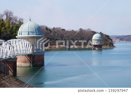 一座經典的圓頂取水塔漂浮在多摩湖(村山水庫)上,映襯著藍天。 一座經典的圓頂取水塔漂浮在多摩湖(村山水庫)上,映襯著藍天。 139297947
