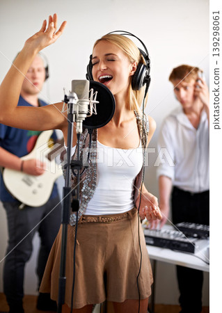 Professional, singing and happy woman with microphone, headphones and band performance with talent. Recording studio, art and girl singer live streaming for music label, sound and audio broadcast. Professional, singing and happy woman with microphone, headphones and band performance with talent. Recording studio, art and girl singer live streaming for music label, sound and audio broadcast. 139298061