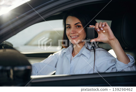 Through the window, holding keys. Woman is sitting in the modern car, happy new owner 139298462