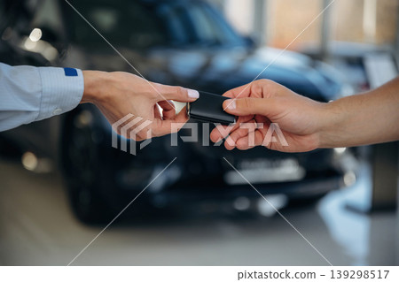 Against the vehicle at background. Close up view of woman's and man's hands that are taking the keys for new car Against the vehicle at background. Close up view of woman's and man's hands that are taking the keys for new car 139298517