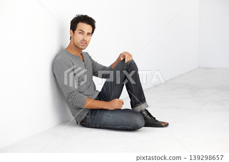 Serious, fashion and portrait of young man by white wall with casual, stylish and trendy outfit. Attractive, confidence and handsome male model from Canada sitting on floor with edgy and cool style. 139298657