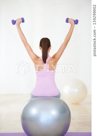 Woman, back and workout on ball, dumbbells and balance in gym, training and strong muscle in arms. Girl, workout and exercise with pilates, weightlifting and hard work for health, wellness and body Woman, back and workout on ball, dumbbells and balance in gym, training and strong muscle in arms. Girl, workout and exercise with pilates, weightlifting and hard work for health, wellness and body 139299002