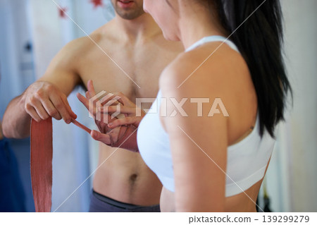 Coach, woman and wrap hands for boxing workout exercise, fight practice at punch club. Man, client and wrist support or tape for healthy fist or athlete bandage for gym sports, challenge for defense Coach, woman and wrap hands for boxing workout exercise, fight practice at punch club. Man, client and wrist support or tape for healthy fist or athlete bandage for gym sports, challenge for defense 139299279