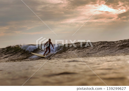 Intense Surfing Maneuver Captured Beneath Dramatic Sky Over Textured Ocean Water Intense Surfing Maneuver Captured Beneath Dramatic Sky Over Textured Ocean Water 139299627