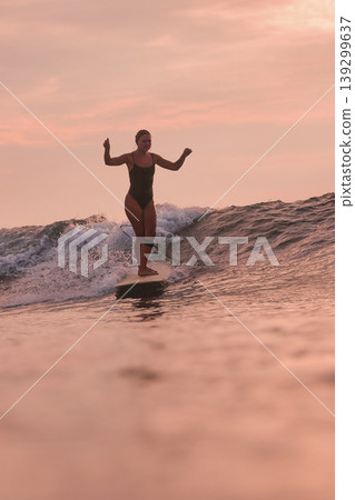 Confident Female Surfer Calmly Handles Gentle Coastal Surf At Dusk 139299637