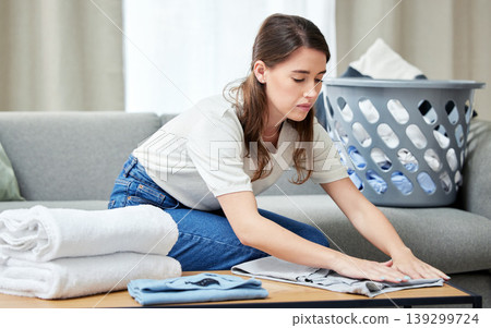 Laundry, woman and fold clothes in living room of home with housekeeping, spring cleaning and housework. Person, cleaner and packing washing on sofa in lounge with basket, serious and domestic work Laundry, woman and fold clothes in living room of home with housekeeping, spring cleaning and housework. Person, cleaner and packing washing on sofa in lounge with basket, serious and domestic work 139299724