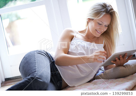 Happy woman, tablet and relax on living room floor for online streaming, entertainment or movie at home. Female person or blonde lying with technology for reading, series or ebook in lounge at house Happy woman, tablet and relax on living room floor for online streaming, entertainment or movie at home. Female person or blonde lying with technology for reading, series or ebook in lounge at house 139299853