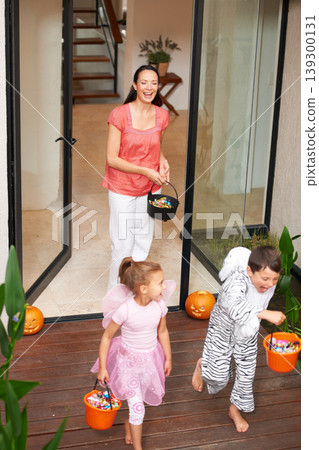 Family house, halloween and children running with candy for fun adventure or vacation tradition. Happy, love and mom watching kids in costume with candy, laugh and energy in costume for holiday prank 139300131