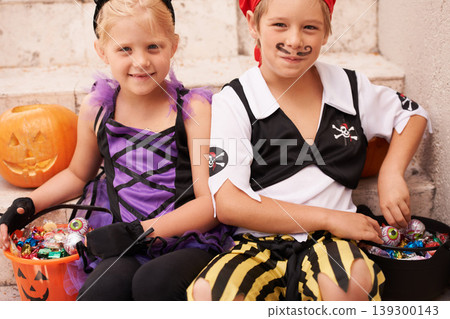 Siblings, portrait and halloween costume on stairs, candy and happiness in childhood. Boy, girl or smile face for holiday party event with trick or treat, theme clothes fairy or pirate by backyard 139300143