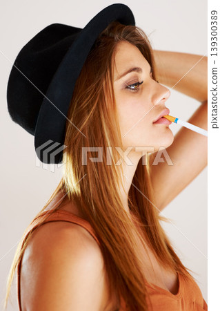 Fashion, cigarette and woman smoking in studio with style, attitude or edgy aesthetic. Smoke, profile and female model smoker pose with cool, confidence and trendy outfit with bad habit or addiction Fashion, cigarette and woman smoking in studio with style, attitude or edgy aesthetic. Smoke, profile and female model smoker pose with cool, confidence and trendy outfit with bad habit or addiction 139300389