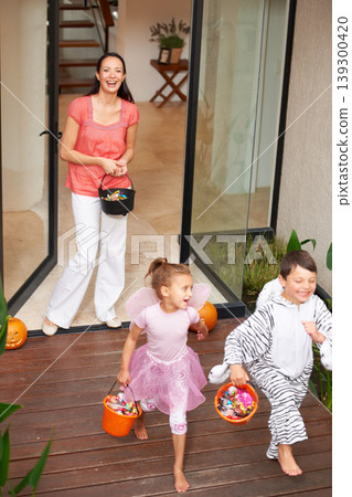 Family home, halloween and children running with candy for fun, adventure or vacation tradition. Happy, love and mother watching excited kids in costume, laugh and playful energy for holiday prank 139300420