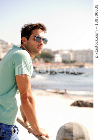 Thinking, fashion and man by ocean in city for summer holiday, vacation and weekend outdoors. Sunglasses, travel and confident person by sea in trendy clothes, style and casual outfit to relax Thinking, fashion and man by ocean in city for summer holiday, vacation and weekend outdoors. Sunglasses, travel and confident person by sea in trendy clothes, style and casual outfit to relax 139300639