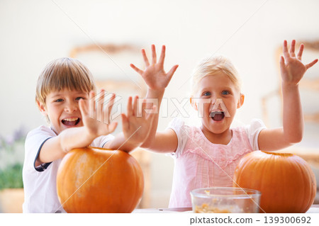 Halloween, hands and carving a pumpkin with children at a home table for fun and bonding. Boy and girl or young kids as siblings together for creativity, holiday lantern and portrait or play in house Halloween, hands and carving a pumpkin with children at a home table for fun and bonding. Boy and girl or young kids as siblings together for creativity, holiday lantern and portrait or play in house 139300692