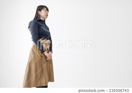 一位年輕女子側身站在白色背景前的肖像照。 一位年輕女子側身站在白色背景前的肖像照。 139300743