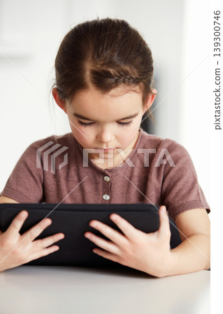 Little girl, tablet and watching on table in living room for online entertainment, games or research at home. Female person, child or kid with technology for communication or networking at house Little girl, tablet and watching on table in living room for online entertainment, games or research at home. Female person, child or kid with technology for communication or networking at house 139300746