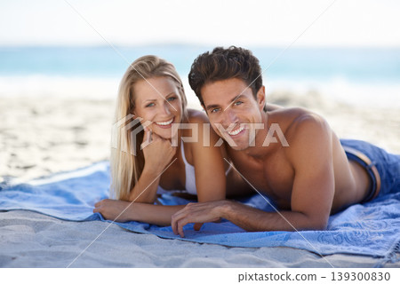 Love, portrait and couple on blanket at beach for date, outdoor bonding or tropical holiday. Romance, man and woman at sea, picnic and relax on ocean vacation together with travel, care and adventure 139300830