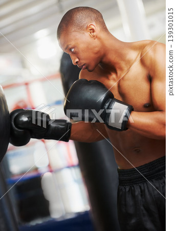 Boxing, gloves and black man training in gym with fitness, power and workout challenge. Strong body, muscle and boxer in club, athlete fighting with bag for exercise and confidence in competition. Boxing, gloves and black man training in gym with fitness, power and workout challenge. Strong body, muscle and boxer in club, athlete fighting with bag for exercise and confidence in competition. 139301015