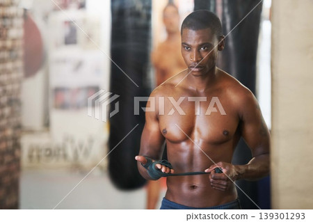 Boxing, wrapping hands and black man in gym for training with fitness, power and workout challenge. Strong body, muscle and boxer with bandage on fist, fearless and confidence in competition fighting Boxing, wrapping hands and black man in gym for training with fitness, power and workout challenge. Strong body, muscle and boxer with bandage on fist, fearless and confidence in competition fighting 139301293