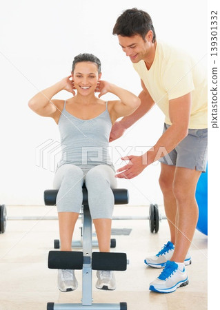 Happy woman, personal trainer and sit ups on bench at gym for workout, exercise or indoor training. Man, coach or instructor helping female person on equipment for strong core or abs at health club Happy woman, personal trainer and sit ups on bench at gym for workout, exercise or indoor training. Man, coach or instructor helping female person on equipment for strong core or abs at health club 139301332