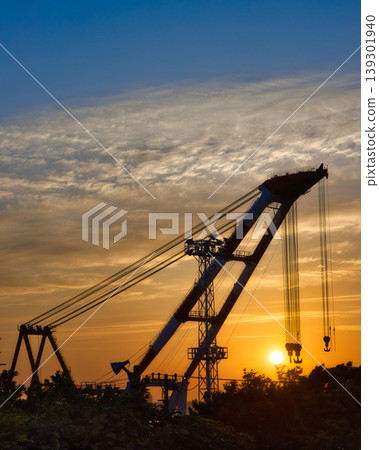The silhouette of a giant crane ship illuminated by the morning sun: a scene from port construction. The silhouette of a giant crane ship illuminated by the morning sun: a scene from port construction. 139301940