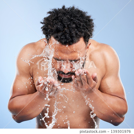 Black man, water and washing face for skincare, hygiene or grooming against a blue studio background. African male person, model and aqua splash for body hydration, shower or facial skin treatment Black man, water and washing face for skincare, hygiene or grooming against a blue studio background. African male person, model and aqua splash for body hydration, shower or facial skin treatment 139301976