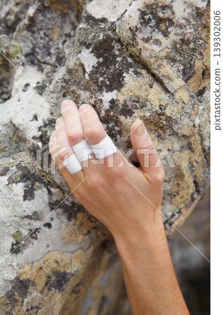 Person, mountain and rock climbing or finger tape on hand for exercise injury, sports grip on nature cliff. Athlete, boulder and hanging for explore peak practice for brave adventure, risk or strong 139302006
