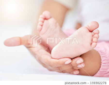Family, love and the feet of a baby in the hands of a parent closeup in the bedroom of their home together. Kids, care or wellness and an infant child on a bed in an apartment with an adult person Family, love and the feet of a baby in the hands of a parent closeup in the bedroom of their home together. Kids, care or wellness and an infant child on a bed in an apartment with an adult person 139302278