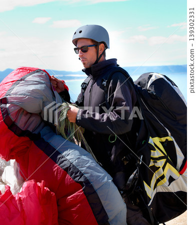 Paragliding, parachute or man in nature for sport, preparation or helmet to exercise for health support. Athlete, training or fitness for outdoor wellness, backpack or safety equipment in countryside Paragliding, parachute or man in nature for sport, preparation or helmet to exercise for health support. Athlete, training or fitness for outdoor wellness, backpack or safety equipment in countryside 139302331