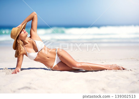 Woman, beach and tanning holiday in bikini on sand for summer travel outdoor peace or tropical paradise. Female person, hat and nature for confidence or sunbathing, weekend trip or water swimsuit Woman, beach and tanning holiday in bikini on sand for summer travel outdoor peace or tropical paradise. Female person, hat and nature for confidence or sunbathing, weekend trip or water swimsuit 139302513