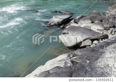 Smooth granite boulders line a turquoise mountain river 139302611