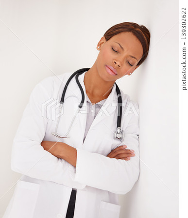 Tired black woman, doctor and sleeping on wall in fatigue, burnout or stress at hospital. Face of exhausted African female person, surgeon or medical nurse asleep or overworked on job at clinic 139302622