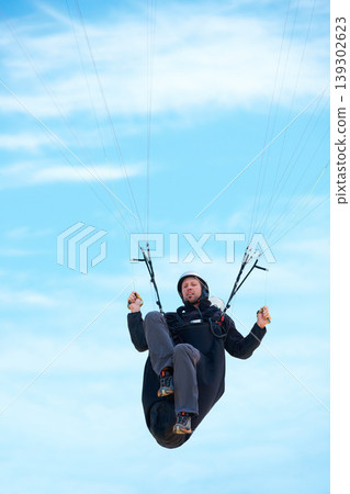 Man, parachute and paragliding in air nature for exercise, healthy adventure with extreme sport. Athlete, glide or fearless for outdoor fitness for health wellness, helmet or safety gear by blue sky Man, parachute and paragliding in air nature for exercise, healthy adventure with extreme sport. Athlete, glide or fearless for outdoor fitness for health wellness, helmet or safety gear by blue sky 139302623