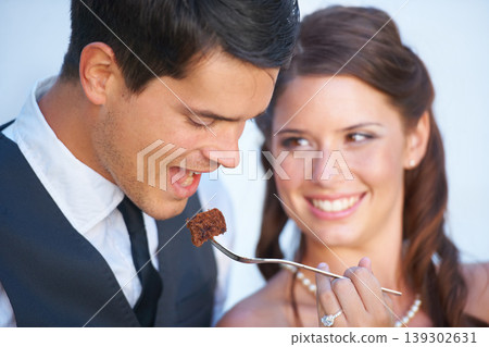 Smile, wedding and couple eating cake together for celebration of love together at party. Happy, cute and young bride feed husband sweet dessert at romantic marriage ceremony or event with commitment 139302631