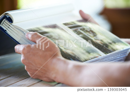 Photo album, photographs and hands of person for memory, reflection and nostalgia in home. Family pictures, thinking and closeup of photos in book to remember past, childhood and memories of youth Photo album, photographs and hands of person for memory, reflection and nostalgia in home. Family pictures, thinking and closeup of photos in book to remember past, childhood and memories of youth 139303045
