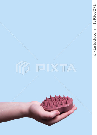 Hair pink scalp massager in woman hand on the pink background isolated. Image with copy space. Mock up for design and banner. Vertical Hair pink scalp massager in woman hand on the pink background isolated. Image with copy space. Mock up for design and banner. Vertical 139303271