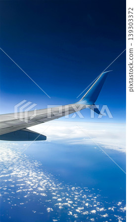 Airplane wing view above clouds with bright sunlight in blue sky. Vertical Airplane wing view above clouds with bright sunlight in blue sky. Vertical 139303372