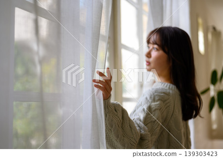 窗邊一位女士向外望去。 窗邊一位女士向外望去。 139303423