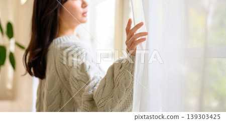 Woman opening curtain Woman opening curtain 139303425