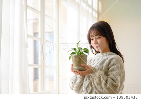 一位女士手持一盆盆栽植物 139303435