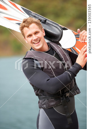 Sports, portrait and man by water with wakeboard for surfing, exercise and recreation hobby by lake. Fitness, extreme sport and excited person with skiing board for freedom, adventure and outdoor fun 139303565